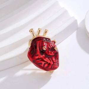 Broche cœur anatomique en émail rouge avec détails dorés sur un support blanc