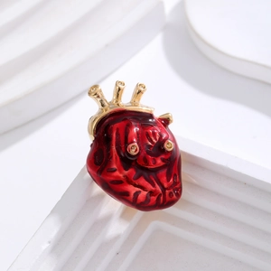 Broche anatomique en émail rouge et or en forme de cœur sur un fond minimaliste