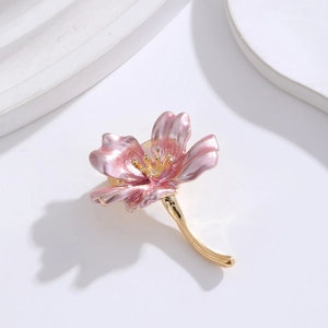 Détail macro d'une broche fleur rose avec étamines dorées et tige métallique courbe