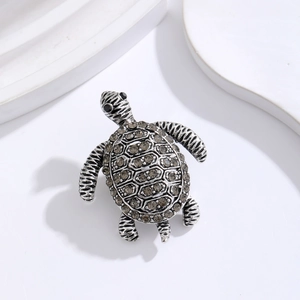 Macro view of vintage silver turtle brooch featuring smoky grey rhinestones and shell texture