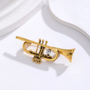Vintage golden flute brooch with sparkling crystal rhinestone on white stone texture background