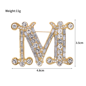Fashionable gold M-letter brooch with shimmering rhinestones and a luxury metal finish