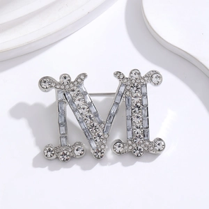 Macro detail of silver M-shaped brooch with inlaid sparkling rhinestones and crystals