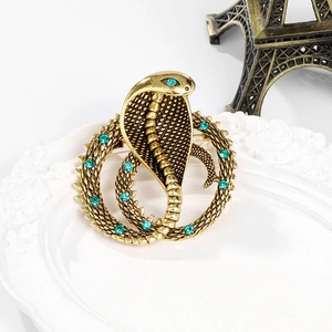 Retro golden cobra snake brooch with blue rhinestones on a white vintage plate