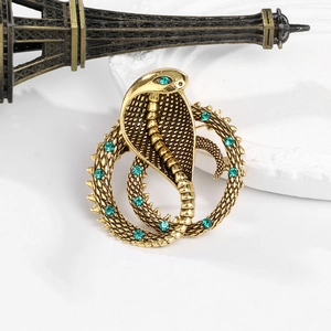 Macro detail of vintage gold cobra brooch with green rhinestones and scale texture