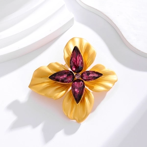 Broche fleur vintage avec pétales dorés mats et cristaux violets sur un support blanc pur