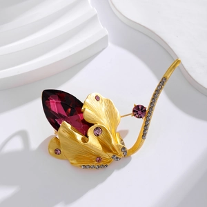 Vintage gold-brushed petal brooch with deep purple gemstone and rhinestones on white
