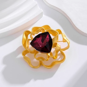 Vintage gold petal brooch with large purple faceted crystal on minimalist white background