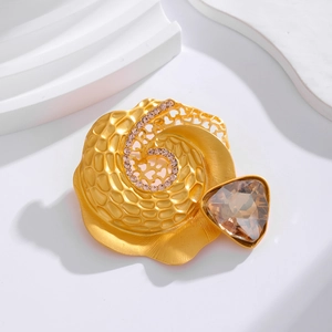 Goldene Spiralbrosche mit bernsteinfarbenem Glas und rosa Strass auf weißem Ständer