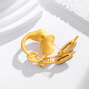 Artistic gold matte tulip leaf brooch with textured finish on minimalist white stairs