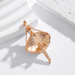 Golden ballet dancer brooch with detailed back pin clasp on minimalist white pedestal