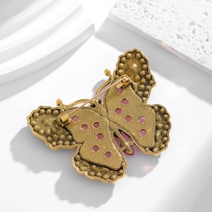 Vintage gold butterfly fairy brooch with colorful gemstones on a white stone background