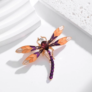 Detail view of dragonfly brooch with orange and purple enamel and pear-cut gemstone