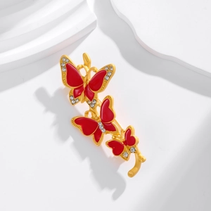 Dettaglio della spilla a tre farfalle in smalto rosso con placcatura in oro e zirconi