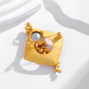 Back view of luxury gold square brooch showing radial texture and safety pin clasp