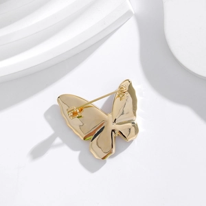Broche papillon dorée avec nacre naturelle montrant la fermeture à épingle au dos