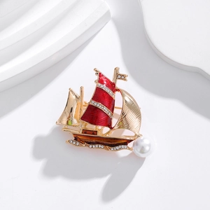 Détail de la broche voilier avec émail rouge, strass étincelants et accent de perle blanche