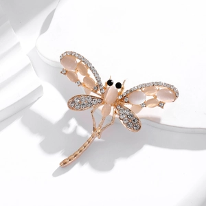 Elegant dragonfly brooch with cat eye stone wings and rhinestones on a white stand