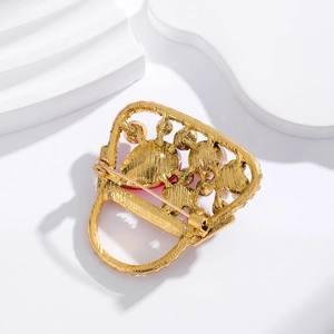 Vintage gouden handtas broche met rood kristal op een witte geometrische standaard