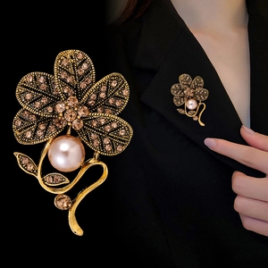 Vintage floral brooch with champagne rhinestones and large pearl on a black suit jacket