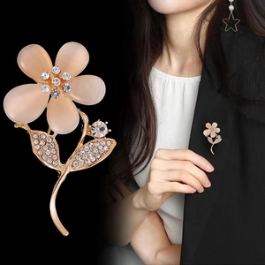 Elegant gold flower brooch with cat eye stone petals and rhinestones on black suit