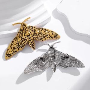 Gothic luna moth brooches in gold and silver finish on elegant white display pedestals