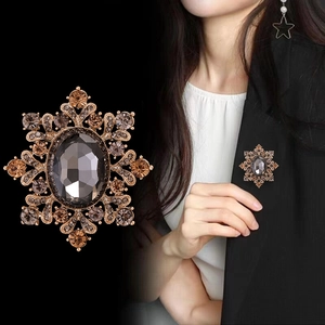 Broche flocon de neige vintage dorée avec gemme grise sur un blazer noir pour femme