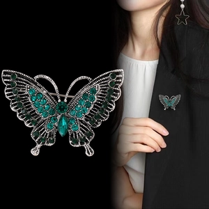Vintage silver hollow butterfly brooch with green crystals on a black suit jacket