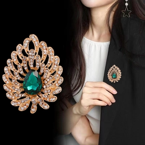 Elegant peacock brooch with green teardrop crystal and sparkling diamonds in gold finish