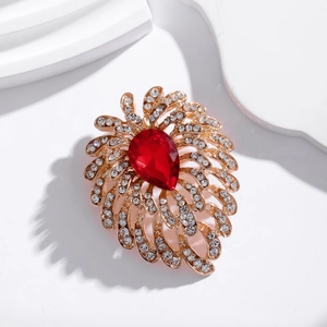 Elegant gold brooch with large red teardrop gemstone and sparkling crystal feathers