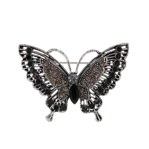 Detail of vintage silver butterfly brooch with black and brown crystals and cutout patterns