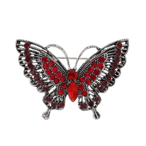 Macro detail of red rhinestone encrusted butterfly brooch with silver metal base