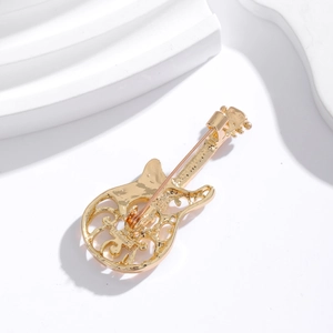 Close-up of guitar brooch back showing golden alloy texture and pin clasp detail
