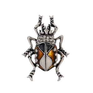 Macro shot of beetle brooch with orange enamel finish and crystal details on white background