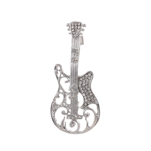 Macro detail of silver guitar brooch with sparkling rhinestones and ornate scrollwork