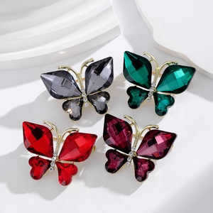 Broches papillons en cristal en quatre couleurs sur un présentoir blanc au style épuré