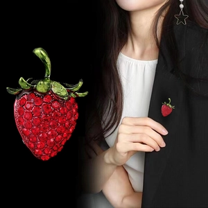 Elegant strawberry brooch with red rhinestones and green leaves shown on a black suit
