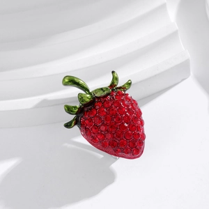 Fashionable strawberry brooch with red rhinestones and green enamel on white background
