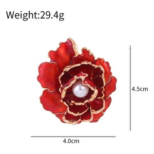 Luxurious red enamel peony brooch with gold trim and pearl center on white background
