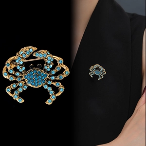 Luxuriöse goldene Krabbenbrosche mit blauen Strasssteinen am schwarzen Revers