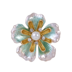 Elegant gold flower brooch with white pearl and green enamel petals on white background