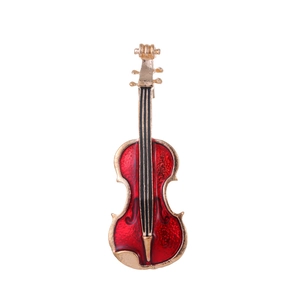 Détail d'une broche violon vintage dorée avec finition en émail rouge éclatant