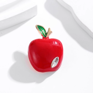 Broche pomme rouge émaillée avec feuille verte et strass sur un socle blanc pur