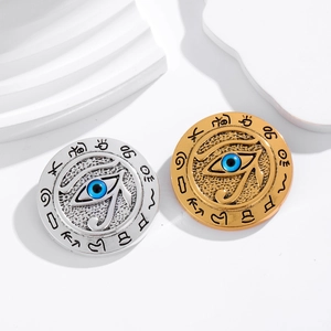 Gold and silver Egyptian Eye of Horus brooches with blue evil eye on white pedestal