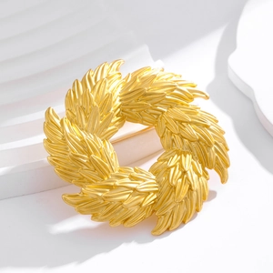 Vintage golden olive branch wreath brooch in matte finish shown on a white geometric stage