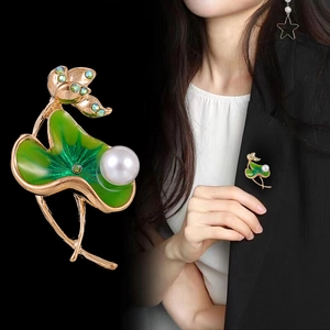 Elegant lotus leaf brooch with green enamel, crystals and white pearl on black background