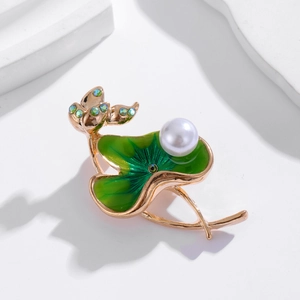 Elegant lotus and leaf brooch with green enamel and pearls on a white stone pedestal
