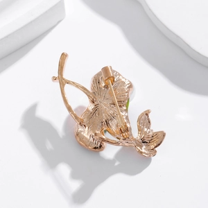 Golden lotus pearl brooch with green enamel and safety pin back on white stone