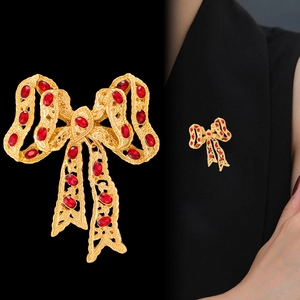 Vintage gold bow brooch with red rhinestones, shown on black background and model