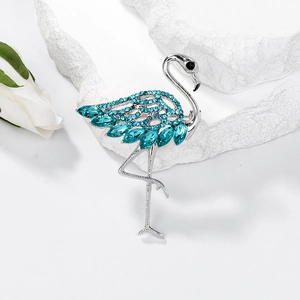 Elegant flamingo brooch with blue crystals and marquise stones on white rose background